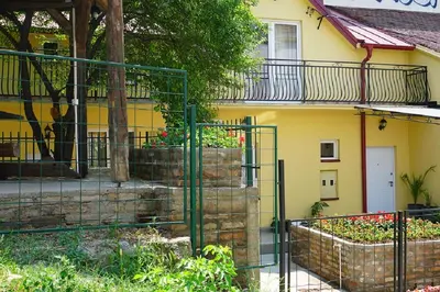 a fence in front of a yellow house with plants at Male stepenice in Belgrade