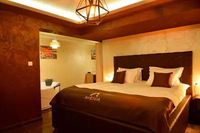 a bedroom with a large bed and a bathroom at Avenia Restaurant & Apartments in Ruma