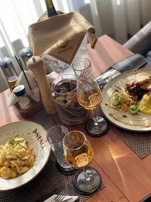 a table with plates of food and glasses of wine at Avenia Restaurant & Apartments in Ruma
