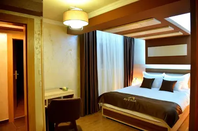 a bedroom with a bed and a chair in a room at Avenia Restaurant & Apartments in Ruma