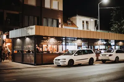 a white van parked in front of a store at Avenia Restaurant & Apartments in Ruma
