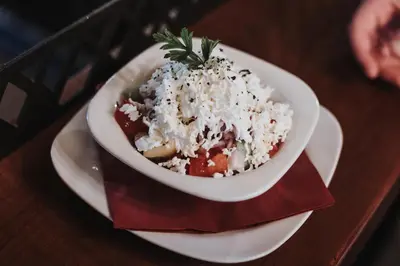 a bowl of food on a plate on a table at Avenia Restaurant & Apartments in Ruma