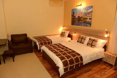 a hotel room with two beds and a chair at Talismano Apartments in Smederevo