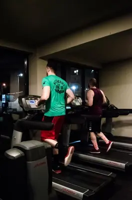 two people running on a treadmill in a gym at Hotel Ub Business & Wellness in Ub