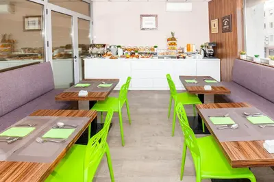 a dining room with wooden tables and green chairs at Adresa Suites in Belgrade