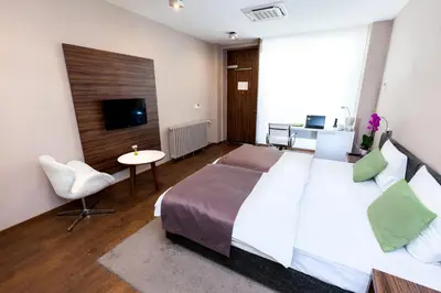 a bedroom with a large bed and a table and a tv at Adresa Suites in Belgrade