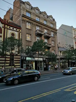 two cars parked in front of a large building at Apartman Rale in Belgrade