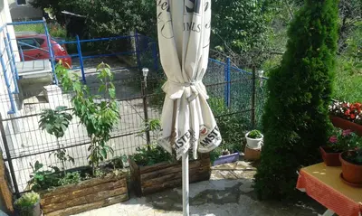 a white umbrella standing in a garden with plants at MaryAnne in Ledine