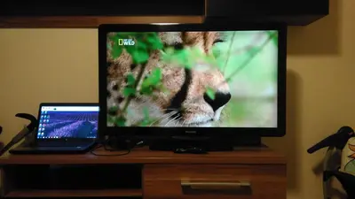 a television on a wooden stand with a laptop at MaryAnne in Ledine