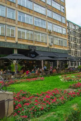 a building with tables and flowers in front of it at Apartment Petra 071 in Belgrade