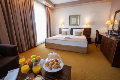 a hotel room with a bed and a table with a bowl of fruit at Hotel Monogram Park in Ruma