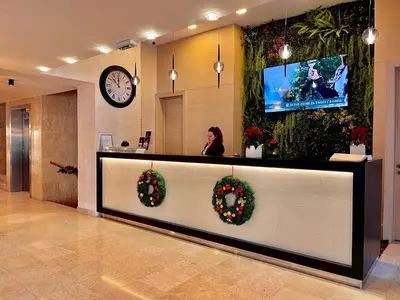 a woman in a lobby with christmas wreaths at Hotel Monogram Park in Ruma