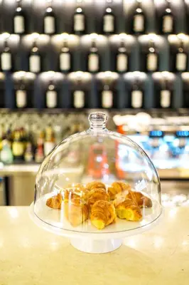 a glass plate of pastries in a glass dome on a table at Hotel Monogram Park in Ruma