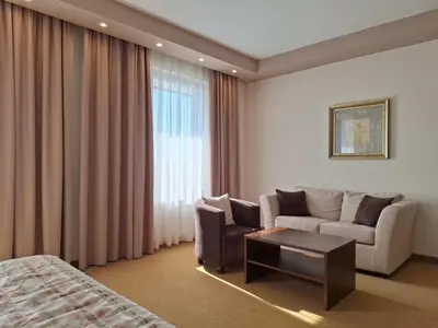 a hotel room with a bed and a couch and a table at Hotel Monogram Park in Ruma