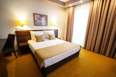 a hotel room with a bed and a desk and a window at Hotel Monogram Park in Ruma