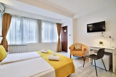 a bedroom with a bed and a desk and a chair at Garni House 46 Plus in Belgrade