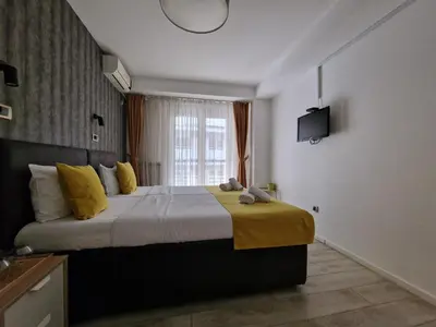 a bedroom with a large bed with a yellow blanket at Garni House 46 Plus in Belgrade