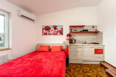 a bedroom with a red bed and a kitchen at Lux Apartment in Downtown in Belgrade