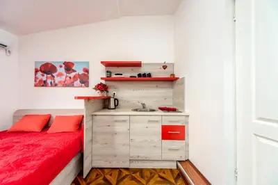 a small bedroom with a red bed and a sink at Lux Apartment in Downtown in Belgrade