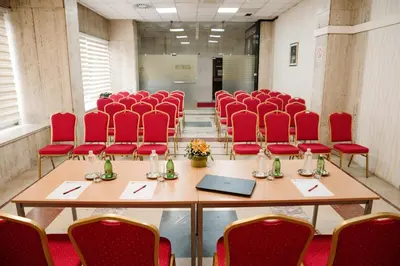 a conference room with red chairs and tables and a laptop at Hotel Slavija in Belgrade