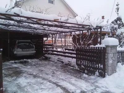 a driveway covered in snow with a fence and a car at Djurdja 2 Apartman in Arandjelovac