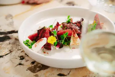 a white bowl of food with a glass of wine at Metropol Palace, Belgrade in Belgrade
