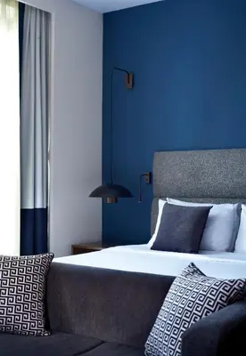 a blue bedroom with a bed and a blue wall at Metropol Palace, Belgrade in Belgrade
