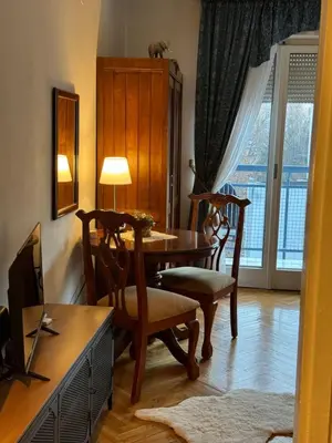 a dining room with a table and chairs and a television at Principessa Apartment in Belgrade