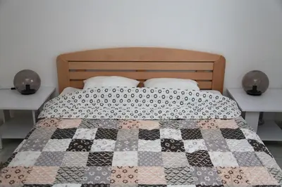 a bed with a quilt on it with two night stands at Petars Apartment in Belgrade