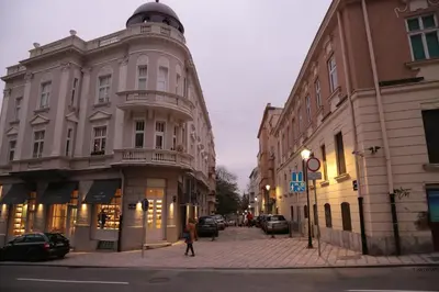 a woman walking down a street next to buildings at Petars Apartment in Belgrade