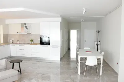 a kitchen with white cabinets and a table and chairs at Lux House Olga in Ruma