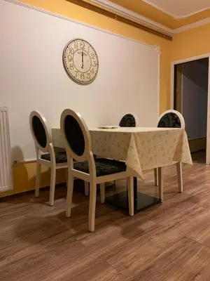 a dining room table with four chairs and a clock on the wall at Bellmatini in Belgrade