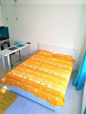 a bedroom with a bed with an orange blanket at Asya Studio in Belgrade
