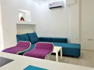 a living room with a blue couch and two purple chairs at Asya Blue Apartment in Belgrade