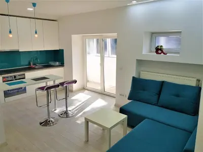 a living room with a blue couch and a kitchen at Asya Blue Apartment in Belgrade