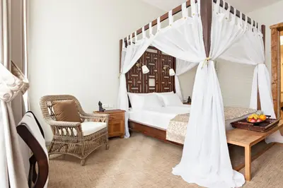 a bedroom with a canopy bed and a chair at SuperB Luxury Suites in Belgrade