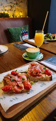a plate with two slices of pizza and a glass of orange juice at SuperB Luxury Suites in Belgrade