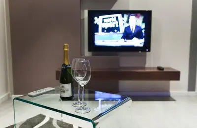 a bottle of champagne and a wine glass on a glass table at Central Apartments in Belgrade