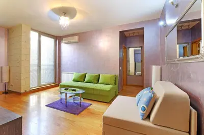 a living room with a green couch and a table at Apartment Paradise Symphony in Belgrade