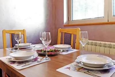 a wooden table with plates and wine glasses on it at Apartment Paradise Symphony in Belgrade