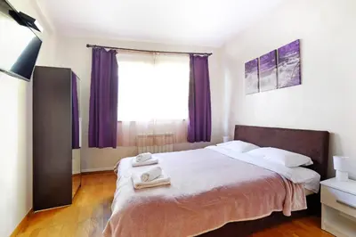 a bedroom with a large bed with purple curtains at Apartment Paradise Symphony in Belgrade