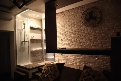a bathroom with a glass shower with a brick wall at Al Mattina Apartments Belgrade in Belgrade