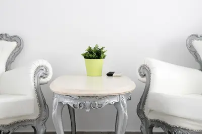 a white table with a yellow vase on it between two chairs at Natalie's Suite in Belgrade