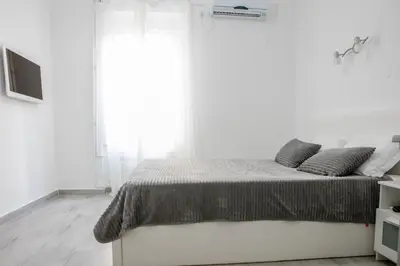 a white bedroom with a bed and a large window at Natalie's Suite in Belgrade