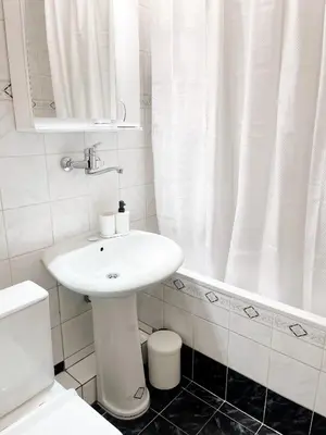 a white bathroom with a sink and a bath tub at Cherry Apartment Arena in Belgrade