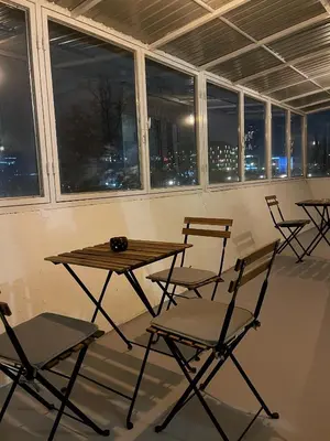 a table and chairs in a room with windows at Cherry Apartment Arena in Belgrade