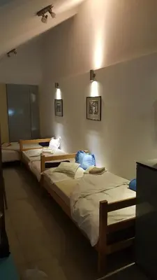 three beds in a room with lights on the wall at Green point Apartments in Dušanovac (historical)