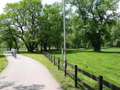 two people riding bikes down a path in a park at Monia Dream Apartment - Belgrade Lake & Fair in Belgrade