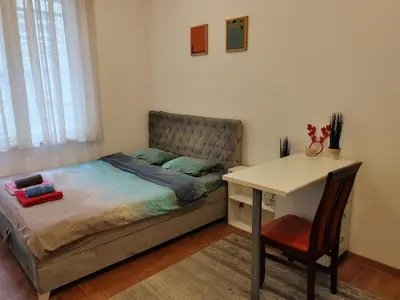 a bedroom with a bed with a desk and a table at Belvedere city center apartment in Belgrade