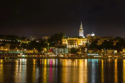 a city lit up at night next to the water at Belvedere city center apartment in Belgrade